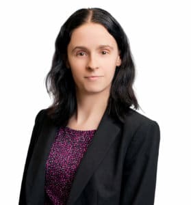 Corporate headshot of Danielle wearing a purple shirt and black blazer on a white backdrop